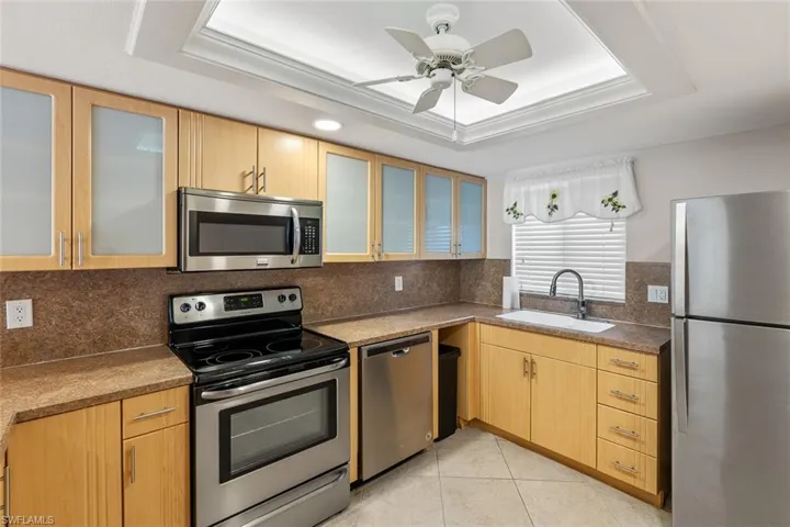 Kitchen featuring sink, a tray ceiling, tasteful backsplash, and appliances with stainless steel finishes
