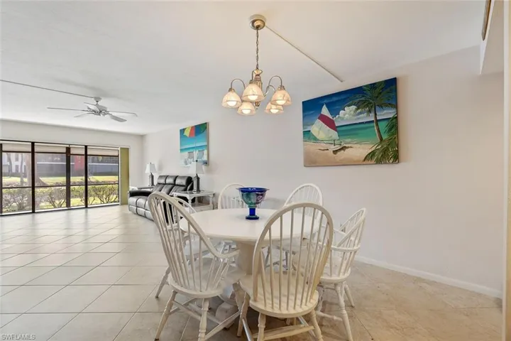Dining space with light tile flooring and ceiling fan with notable chandelier