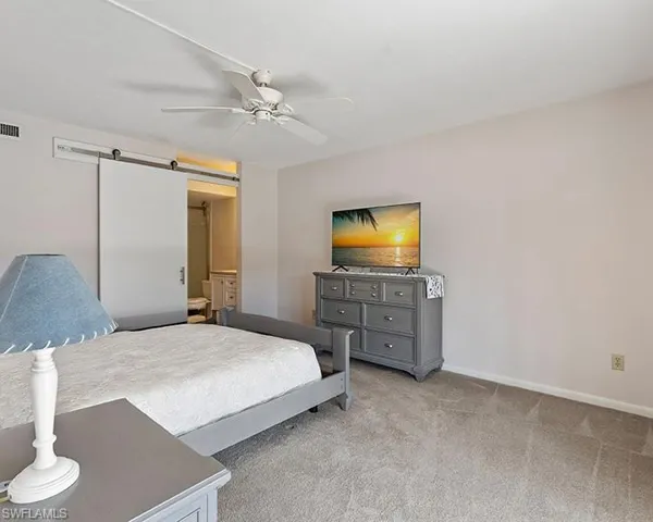 Bedroom featuring a barn door, ceiling fan, and carpet floors