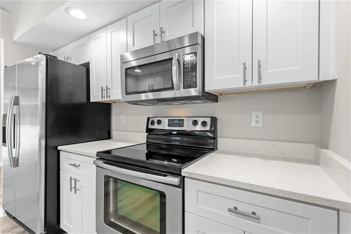 Kitchen featuring stainless steel appliances, light stone counters, and white cabinets