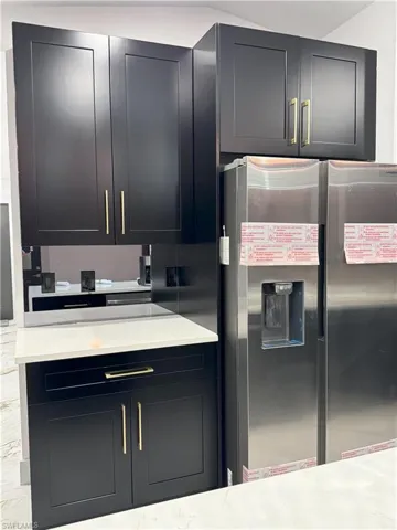Kitchen featuring light stone counters and stainless steel fridge with ice dispenser