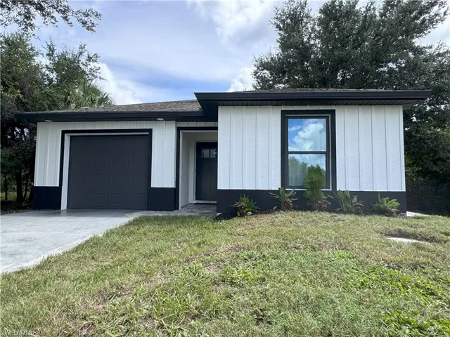 View of front of home with a garage and a front lawn