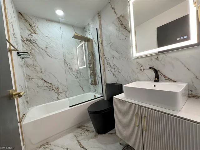 Full bathroom featuring toilet, vanity, tile patterned floors, tile walls, and tiled shower / bath