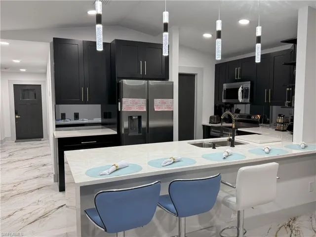 Kitchen with appliances with stainless steel finishes, lofted ceiling, a breakfast bar area, and kitchen peninsula