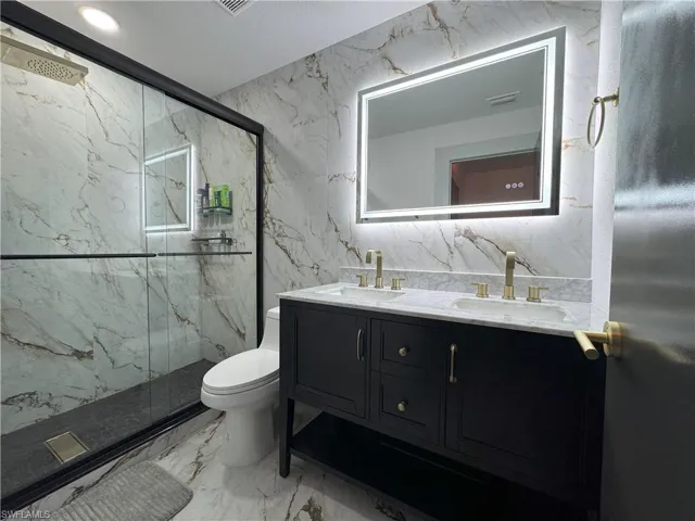 Bathroom with vanity, tile patterned floors, tile walls, toilet, and walk in shower
