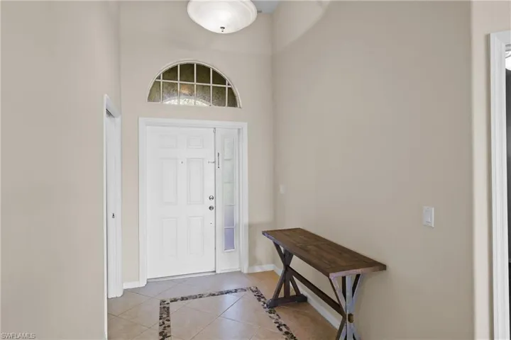 Foyer featuring light tile patterned flooring, inlaid floor details, and a high ceiling
