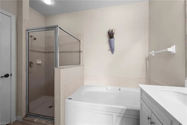 Primary Full Bathroom featuring a garden tub, dual vanity, and a stall shower