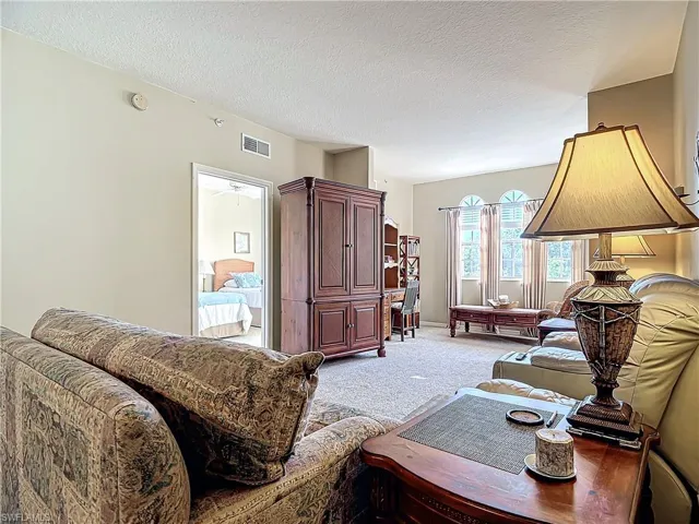 Carpeted living room featuring a textured ceiling and ceiling fan