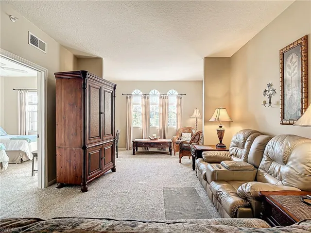 Living room featuring plenty of natural light, light colored carpet, and a textured ceiling