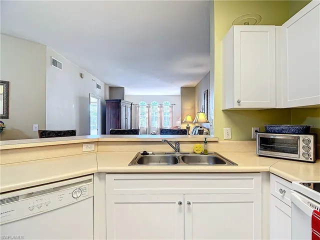 Kitchen featuring white cabinets, kitchen peninsula, white appliances, and sink