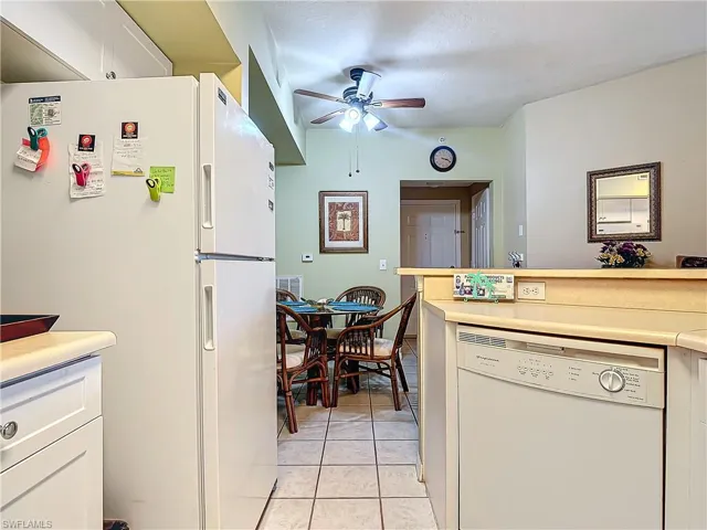 Kitchen with white cabinets, white appliances, ceiling fan, and light tile patterned flooring