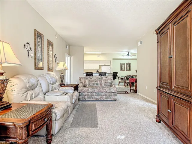Living room with ceiling fan and light colored carpet