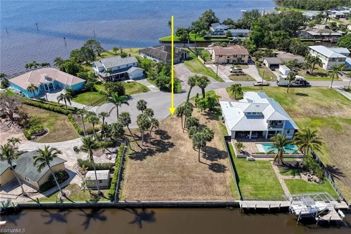 Aerial view of residential area featuring a nearby body of water and a pool area