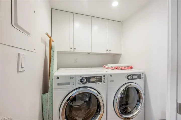 Laundry room featuring independent washer and dryer and cabinets for storage.