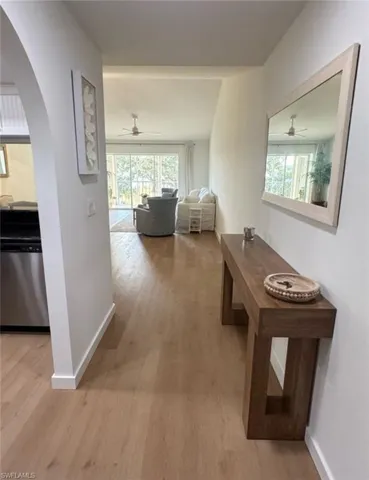 Hallway featuring plenty of natural light, light wood-style flooring, and arched walkways