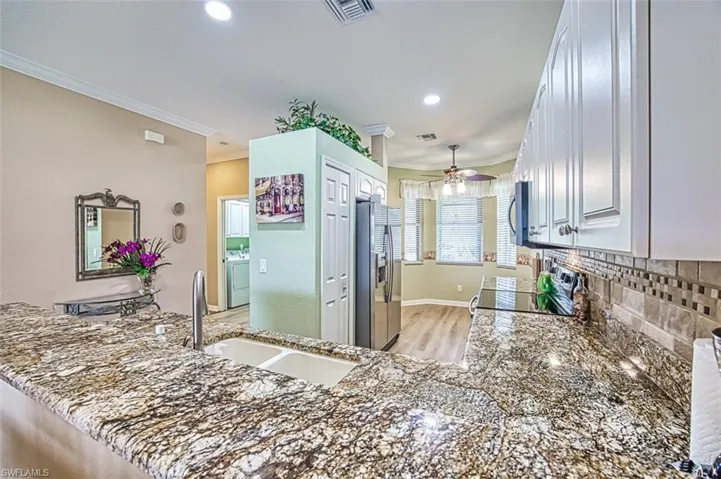 Kitchen with appliances with stainless steel finishes, ceiling fan, kitchen peninsula, and crown molding