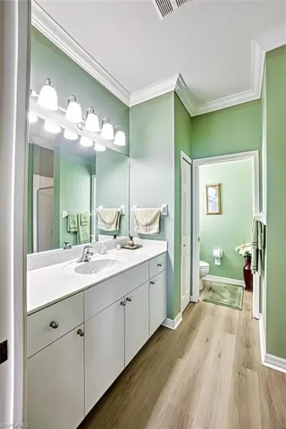 Bathroom with a textured ceiling, vanity, an enclosed shower, toilet, and hardwood / wood-style flooring
