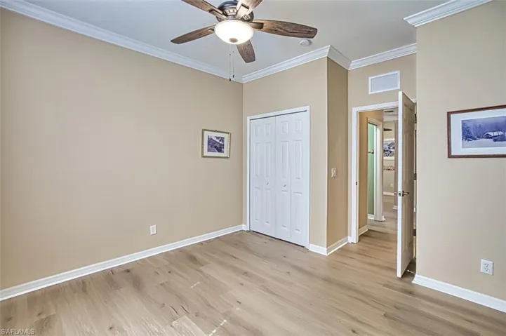 Unfurnished bedroom featuring crown molding, light hardwood / wood-style flooring, ceiling fan, and a closet