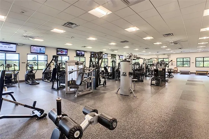 Workout area featuring a paneled ceiling, ceiling fan, and plenty of natural light