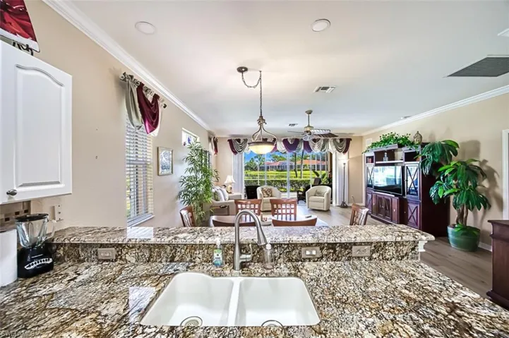 Kitchen with white cabinets, hardwood / wood-style flooring, crown molding, sink, and dark stone counters
