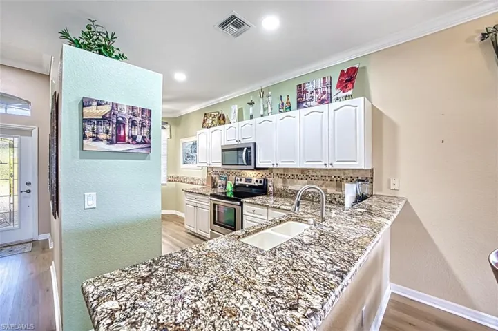 Kitchen with appliances with stainless steel finishes, tasteful backsplash, white cabinetry, and sink