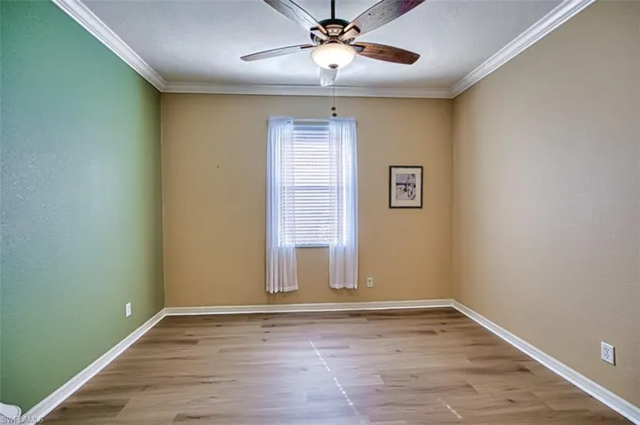 Unfurnished room with light wood-type flooring, ornamental molding, ceiling fan, and a textured ceiling