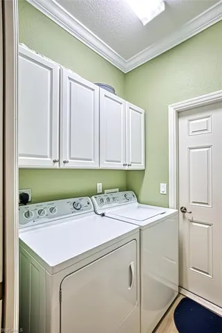Clothes washing area with a textured ceiling, cabinets, and separate washer and dryer