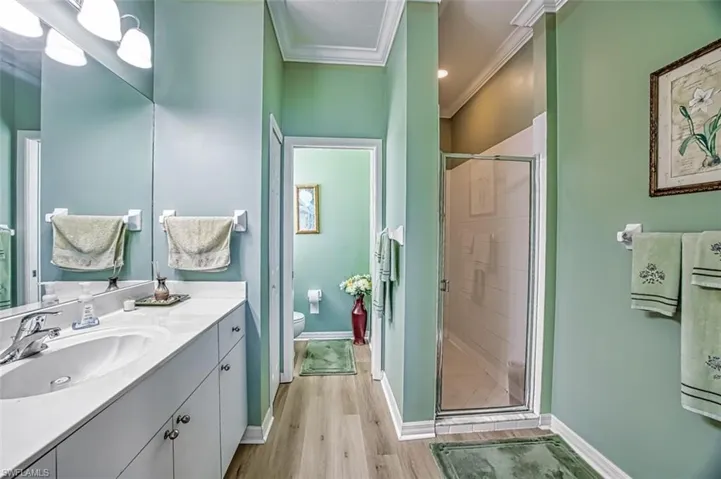 Bathroom with vanity, an enclosed shower, hardwood / wood-style floors, toilet, and ornamental molding