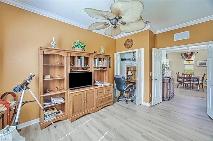 Home office with crown molding, ceiling fan, and light wood-type flooring