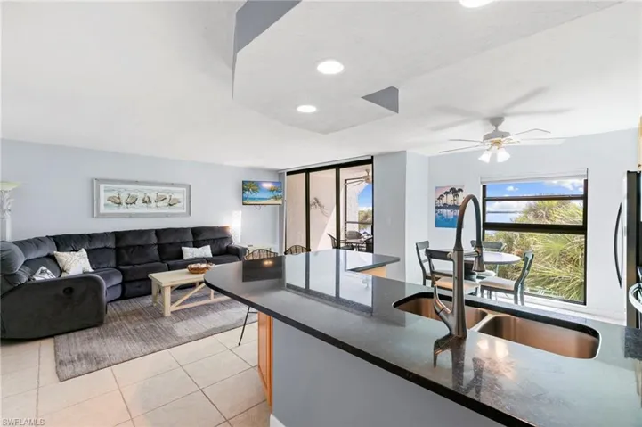 Kitchen featuring light tile patterned floors, recessed lighting, dark stone counters, and open floor plan