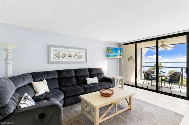 Living area with expansive windows, tile patterned floors, and a ceiling fan