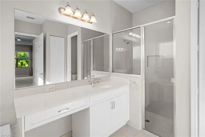 Full bath featuring a stall shower, vanity, light tile patterned flooring, and ceiling fan
