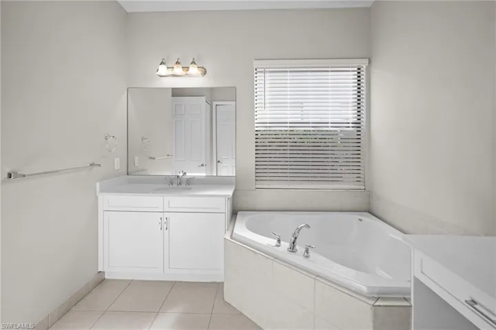 Full bathroom featuring vanity, a garden tub, and light tile patterned flooring