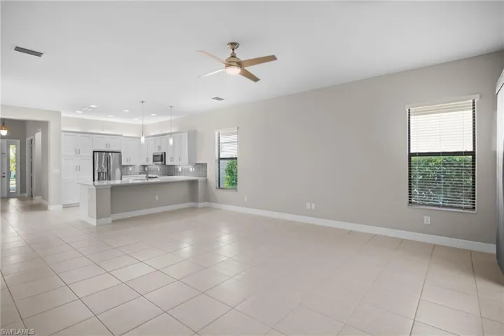 Unfurnished living room featuring healthy amount of natural light, light tile patterned floors, and a ceiling fan