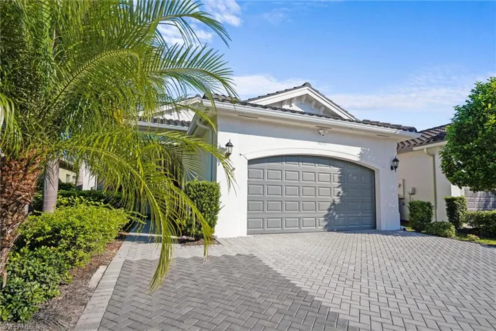 View of front facade with stucco siding, decorative driveway, a tile roof, and an attached garage