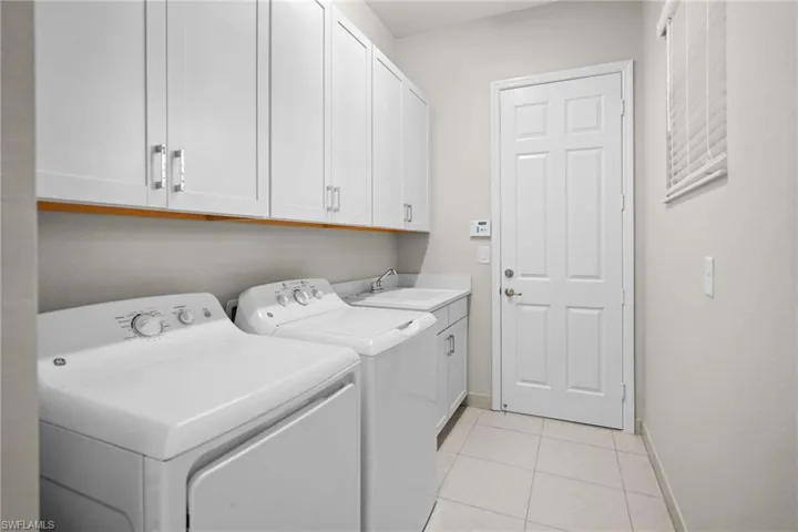 Washroom with light tile patterned floors, cabinet space, and washer and clothes dryer