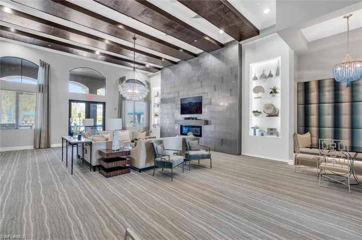 Living room featuring a chandelier, beamed ceiling, a large fireplace, and built in shelves
