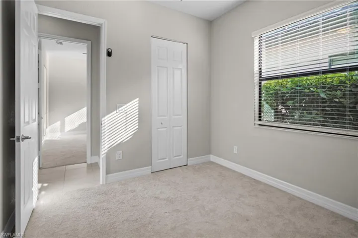 Unfurnished bedroom with light colored carpet, a closet, and light tile patterned floors