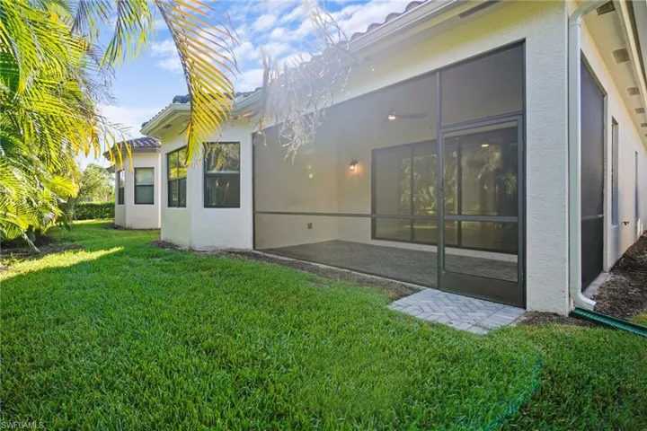 Rear view of property with stucco siding, a yard, and a sunroom