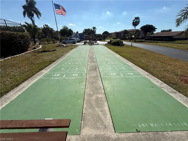 View of home's community featuring shuffleboard and a lawn