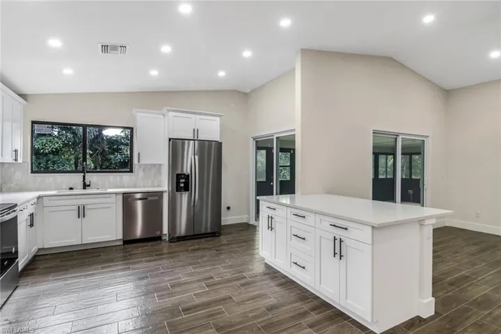 Kitchen featuring white cabinetry, appliances with stainless steel finishes, recessed lighting, wood tiled floors, and backsplash