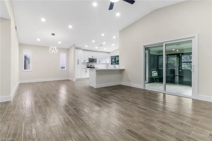 Unfurnished living room with dark wood-style flooring, recessed lighting, vaulted ceiling, and ceiling fan