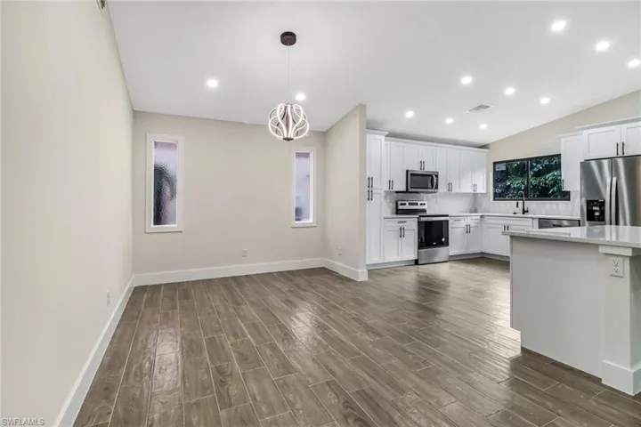 Kitchen featuring stainless steel appliances, pendant lighting, white cabinetry, recessed lighting, and wood finish floors