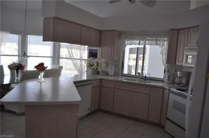 Kitchen with white appliances, a peninsula, light countertops, light tile patterned flooring, and a ceiling fan