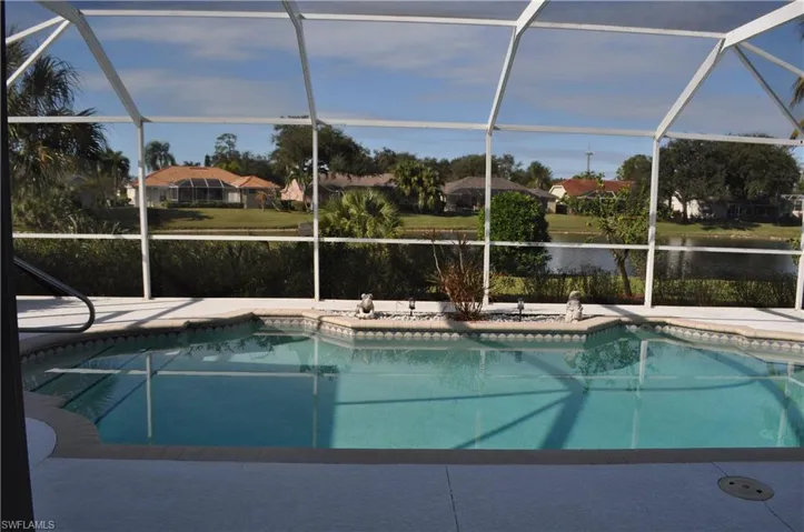 Outdoor pool with a sunroom, a water view, and glass enclosure