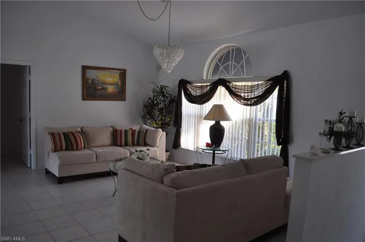 Living area with tile patterned flooring, vaulted ceiling, and a chandelier