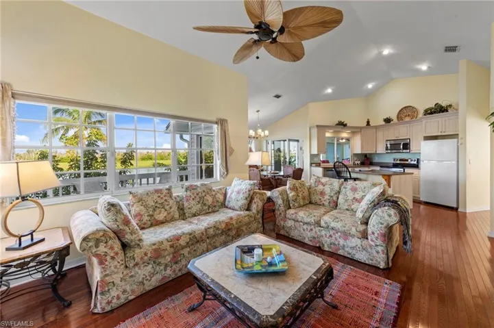 Living area with dark wood-style flooring, a chandelier, high vaulted ceiling, recessed lighting, and ceiling fan