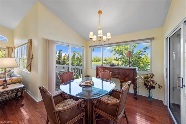 Dining space featuring vaulted ceiling, dark wood-style flooring, healthy amount of natural light, and a chandelier