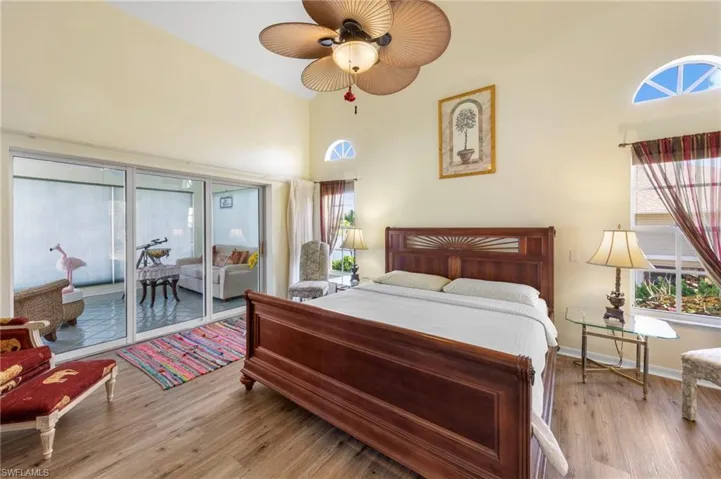 Bedroom with multiple windows, light wood-type flooring, access to outside, a towering ceiling, and ceiling fan