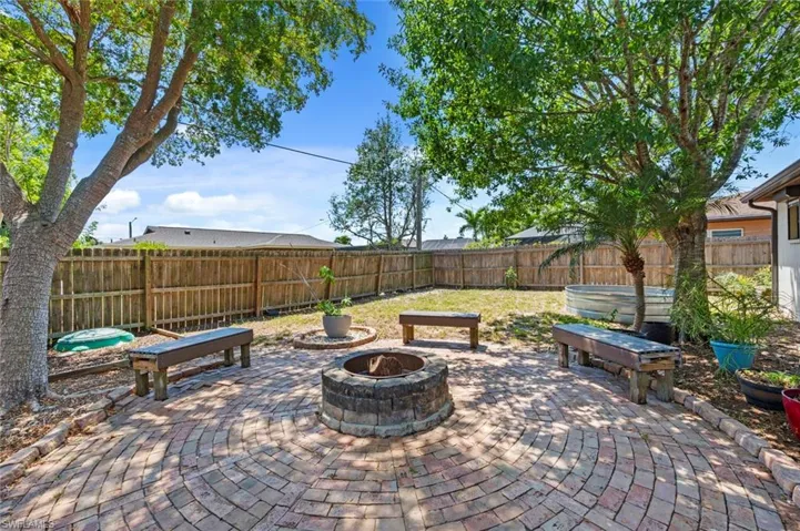 View of patio with a fire pit, a fenced backyard, and a hot tub